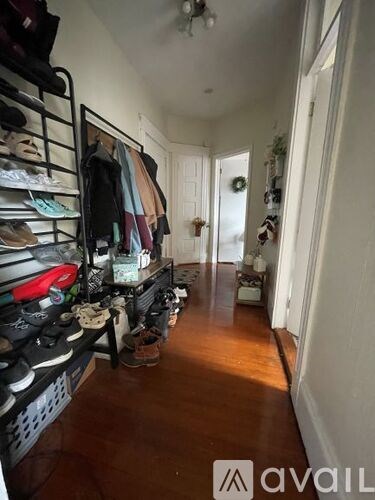 A hallway with a rack of shoes on the left and a doorway on the right.