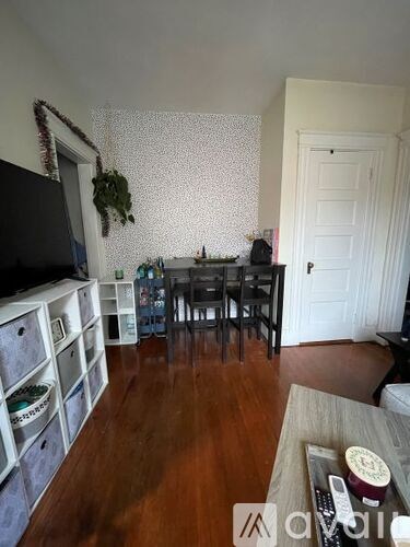 A living room with a wooden floor and a white wallpapered wall.