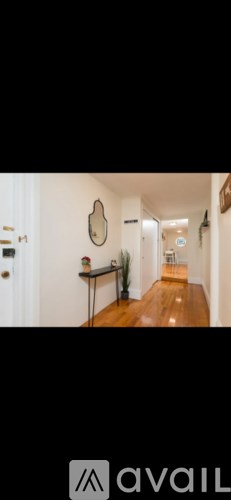 A hallway with a mirror on the wall and a door on the left.