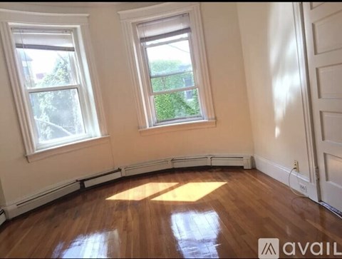 A room with wooden floors and two windows.