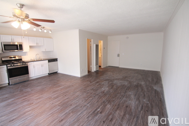 A spacious living room with a kitchen area and hardwood flooring.