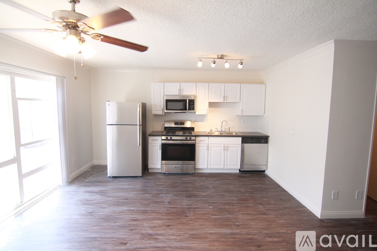A kitchen with white cabinets and a wood floor.