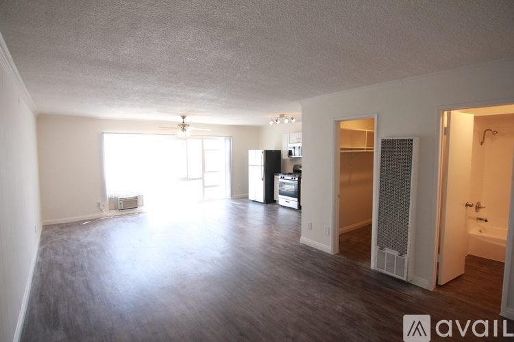 A spacious room with wooden flooring and a large window letting in natural light.