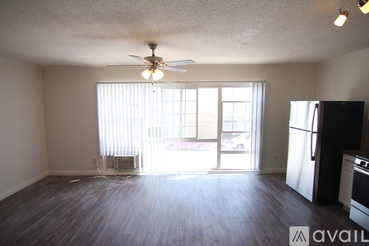 A room with a fan, sliding glass doors, and a refrigerator.