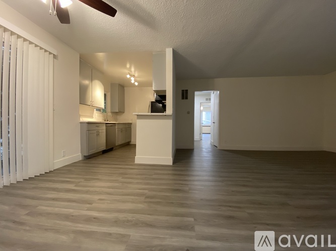 A spacious room with wooden flooring and a ceiling fan.