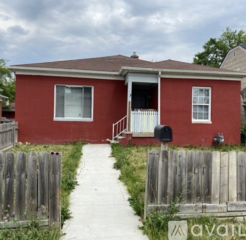 A red house with a mailbox and a wooden fence.