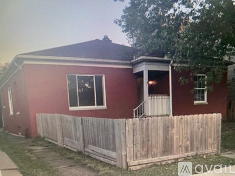 A red house with a white fence in front.
