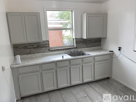 A kitchen with grey cabinets and a window overlooking a brick building.