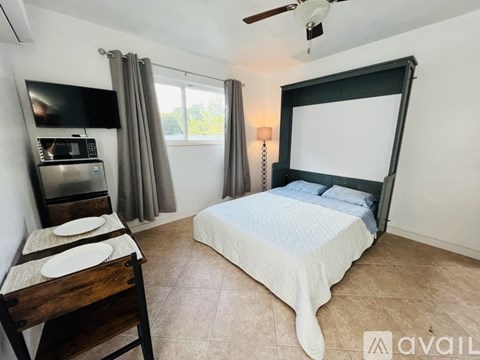 A bedroom with a bed, a chair, and a microwave.