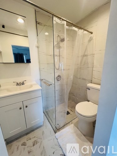 A bathroom with a white toilet, sink, and shower.