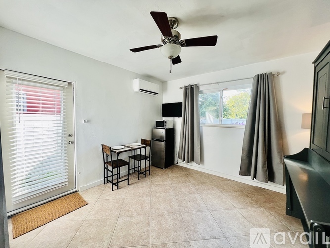 A living room with a ceiling fan and a dining table with chairs.