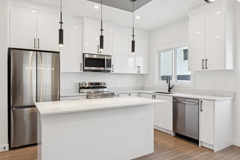 A modern kitchen with white cabinets and stainless steel appliances.