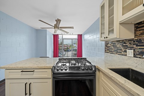 A kitchen with a black stove top oven and a fan.