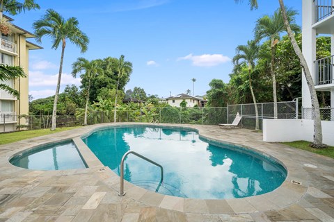 A swimming pool surrounded by palm trees and a white fence.