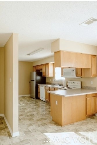 A kitchen with wooden cabinets and a black fridge.