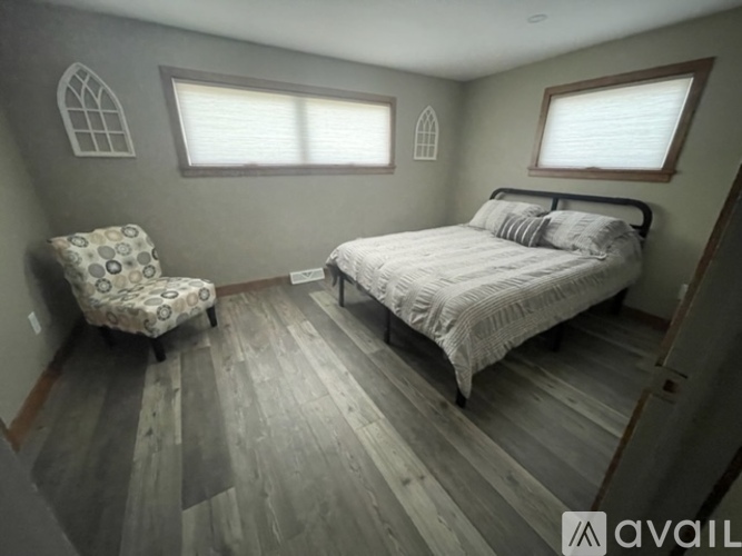 A bedroom with a bed, chair, and window.