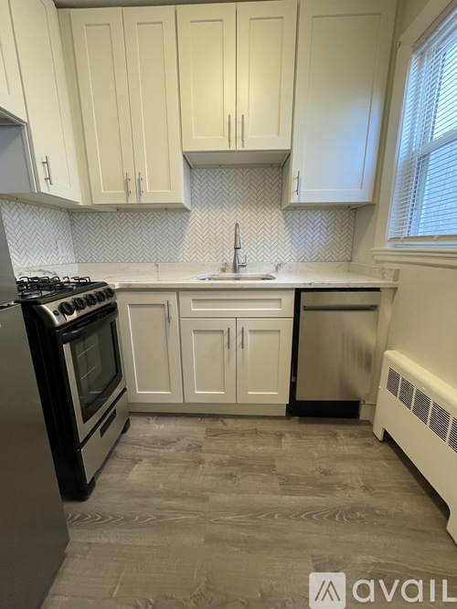 A kitchen with a black stove top oven, white cabinets, and a patterned backsplash.