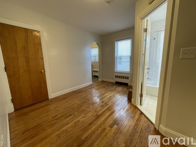 A room with wooden flooring and a door on the left side.