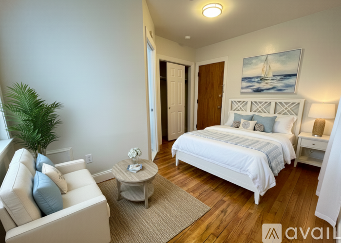 A bedroom with a white bed and a painting of a sailboat on the wall.