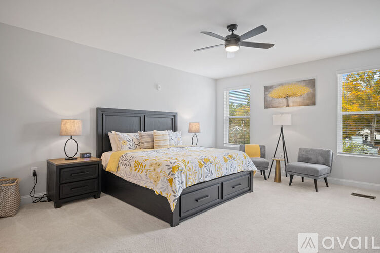 A bedroom with a large bed, a ceiling fan, and a chair.