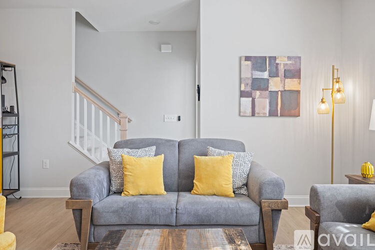 A grey couch with two yellow pillows sits in a living room.