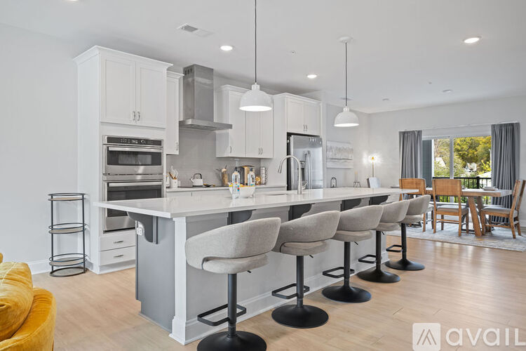 A modern kitchen with white cabinets and a large island with bar stools.