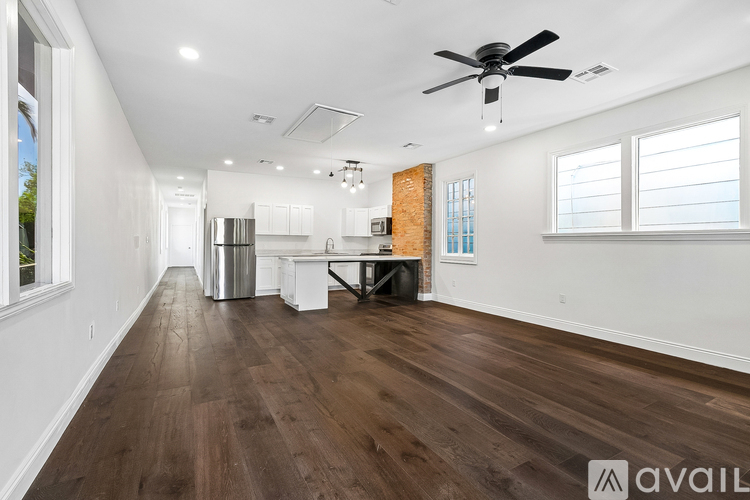 A spacious room with wooden floors and a ceiling fan.