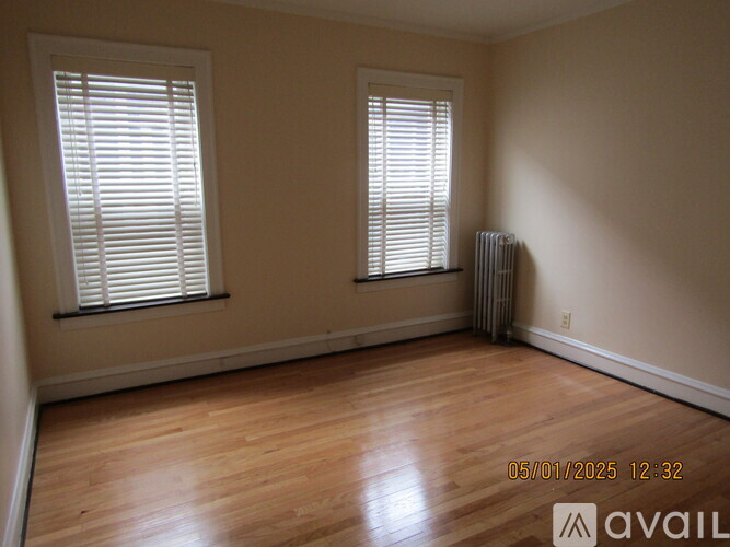 A room with wooden floors and two windows with blinds.