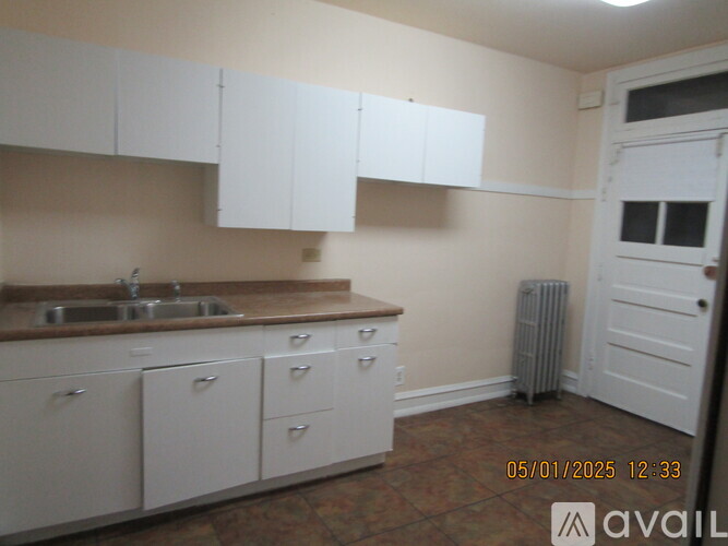 A kitchen with white cabinets and a brown countertop.