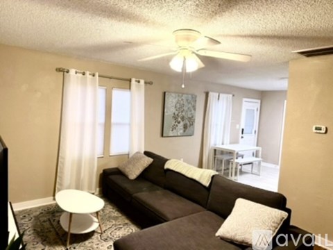 A living room with a brown couch and a white ceiling fan.