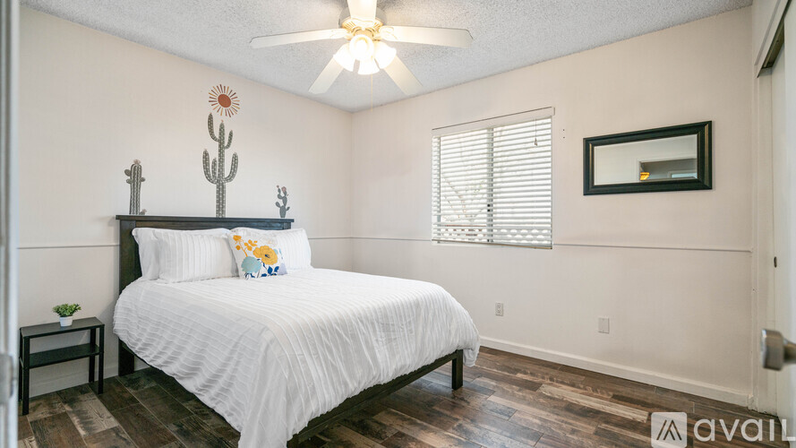 A bedroom with a bed, a cactus decoration, and a ceiling fan.
