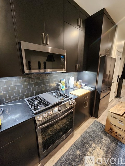 A modern kitchen with black cabinets and a stove top oven.