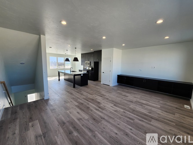 A spacious room with wooden flooring and a large window.