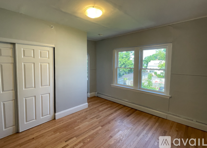 A room with a wooden floor and a window showing greenery outside.