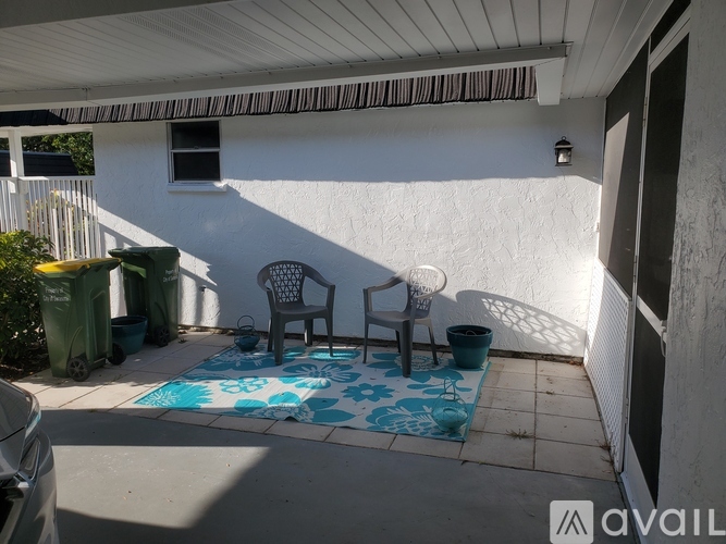 A patio with a blue and white rug, two chairs, and a table.