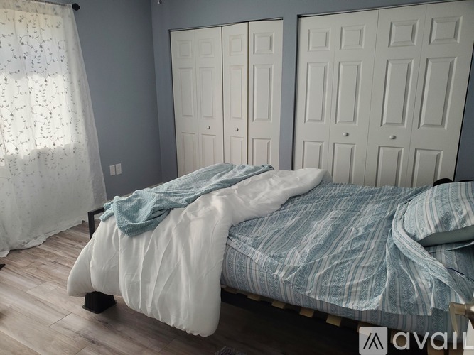 A bedroom with a bed covered in a blue and white striped comforter.