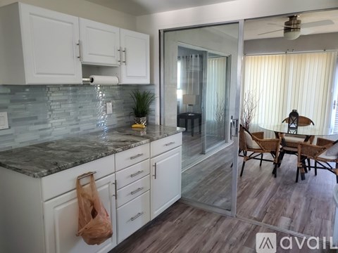 A kitchen with white cabinets and a marble countertop.