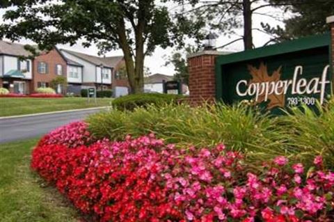 the sign for the copperleaf apartments in front of a garden of flowers