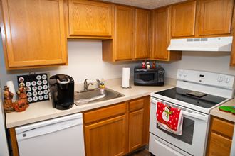 a kitchen with white appliances and wooden cabinets and a sink