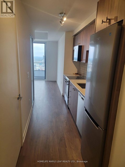 A kitchen with a refrigerator, cabinets and a window.