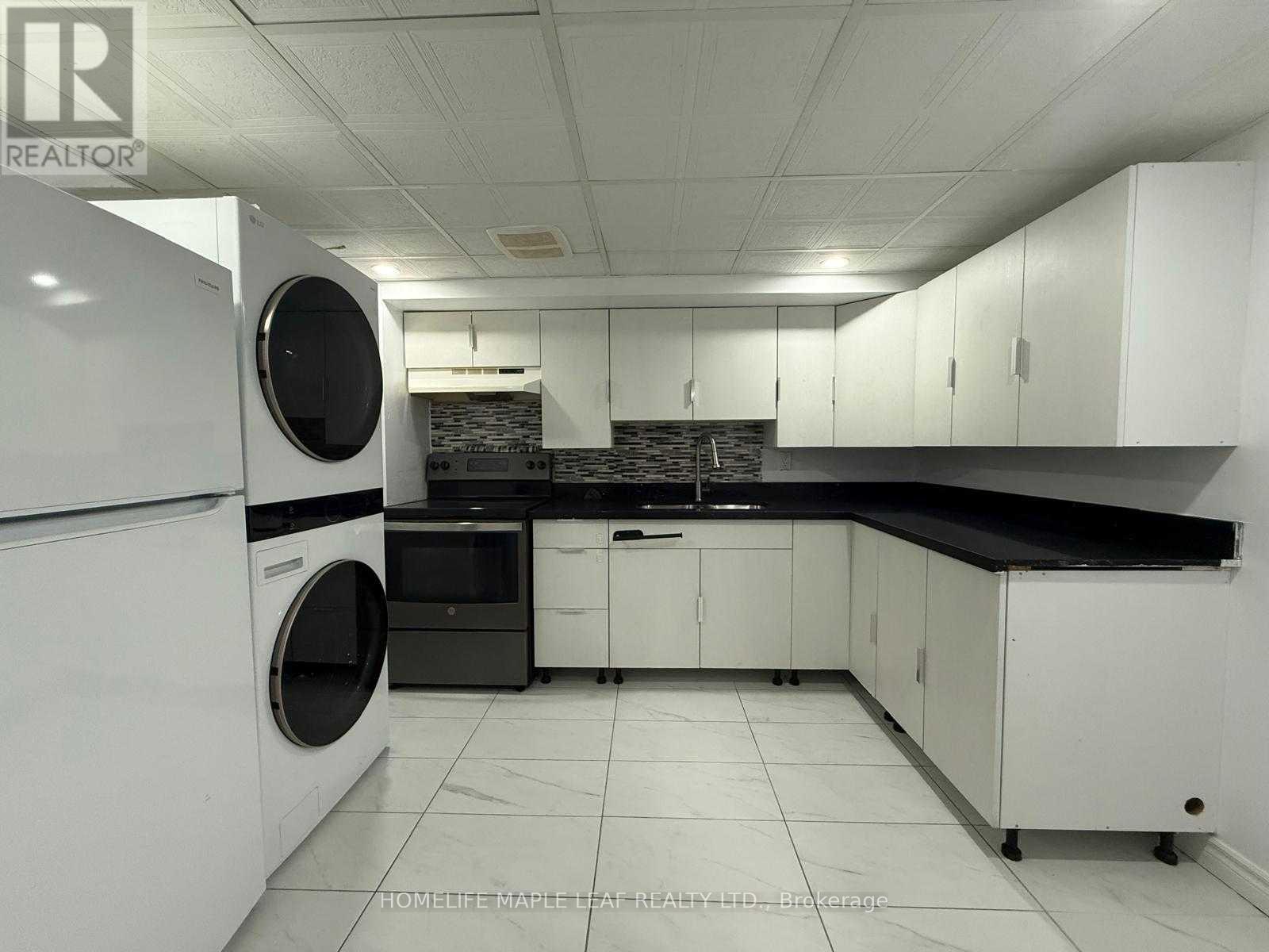 A white kitchen with a black counter top and a washing machine.