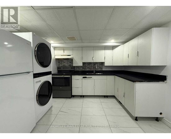 A white kitchen with a black counter top and a washing machine.