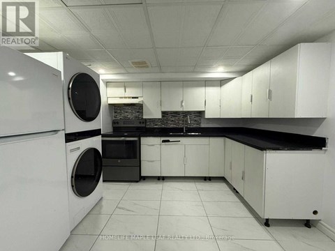 A white kitchen with a black counter top and a washing machine.