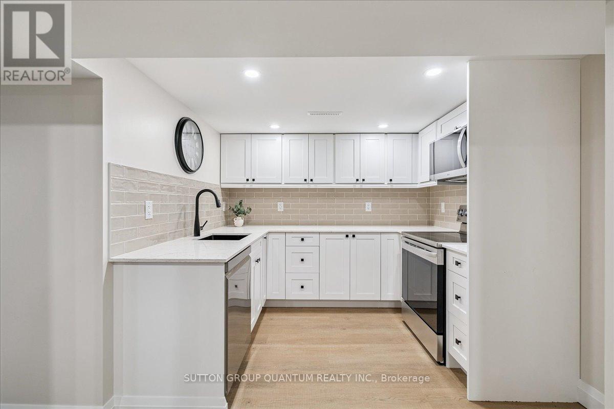 A modern kitchen with white cabinets and a wooden floor.