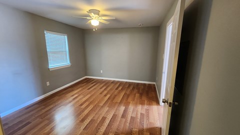 A room with wooden flooring and a ceiling fan.