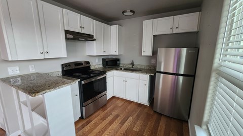 A kitchen with white cabinets and a granite countertop.
