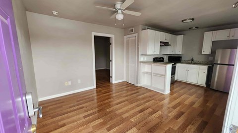 A kitchen with white cabinets and a wooden floor.