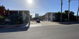 A sunny day in a quiet residential street with a car parked on the side.