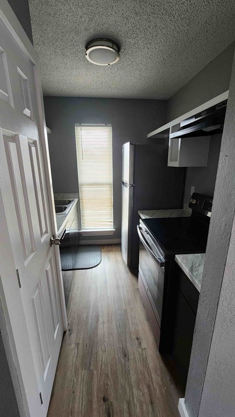 A kitchen with a refrigerator, oven, and sink.