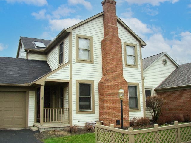 a white house with a brick chimney and a wooden fence
